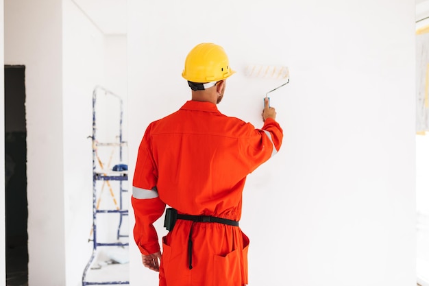 Site foreman painting a wall in a new-build apartment